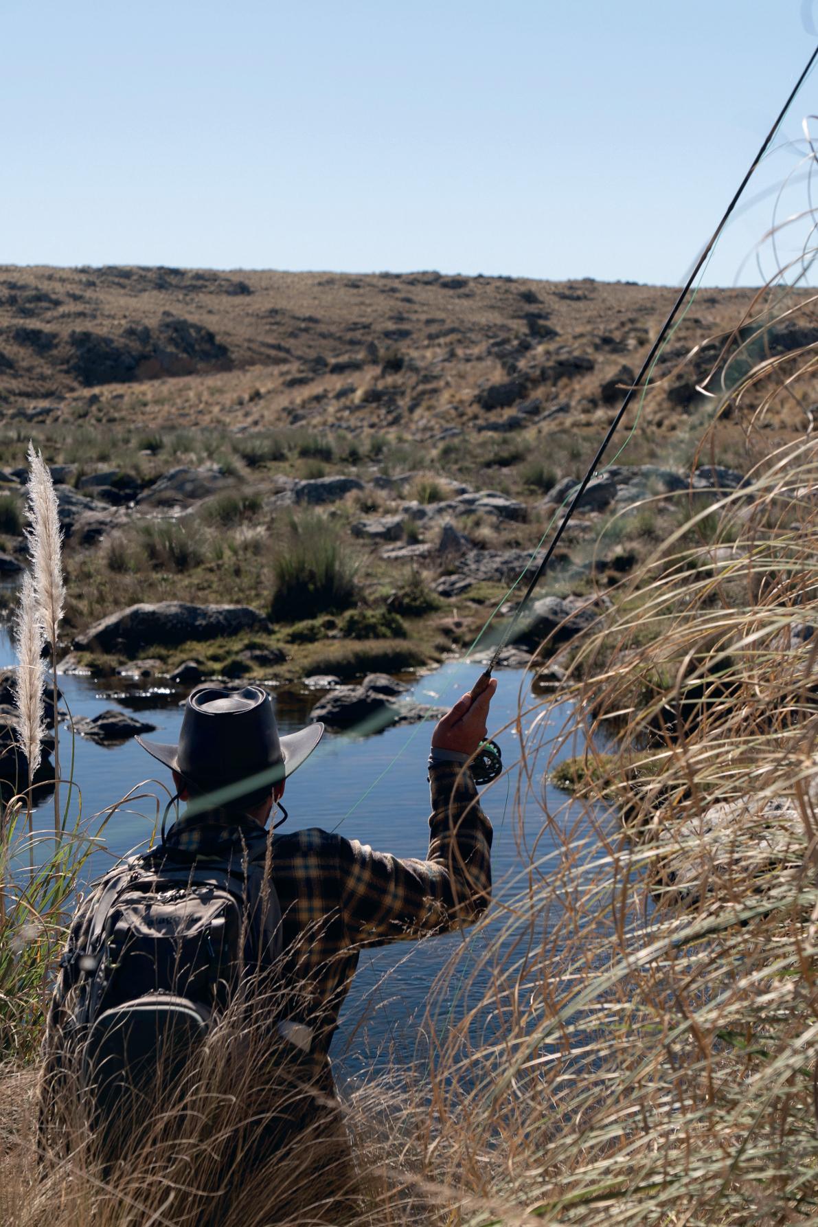 Angler casting a fly rod over a misty mountain stream